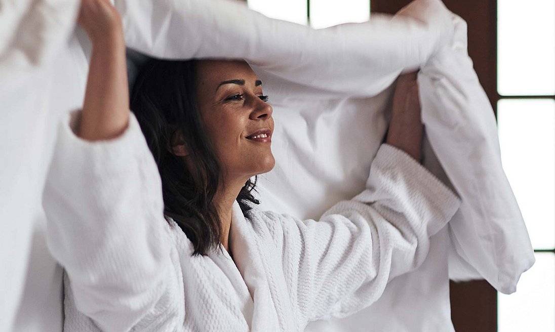 Woman in white bathrobe swings the sheet over herself