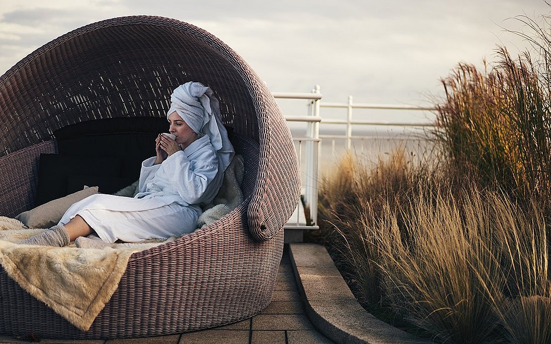 Gast entspannt im Bademantel auf Hotel-Terrasse