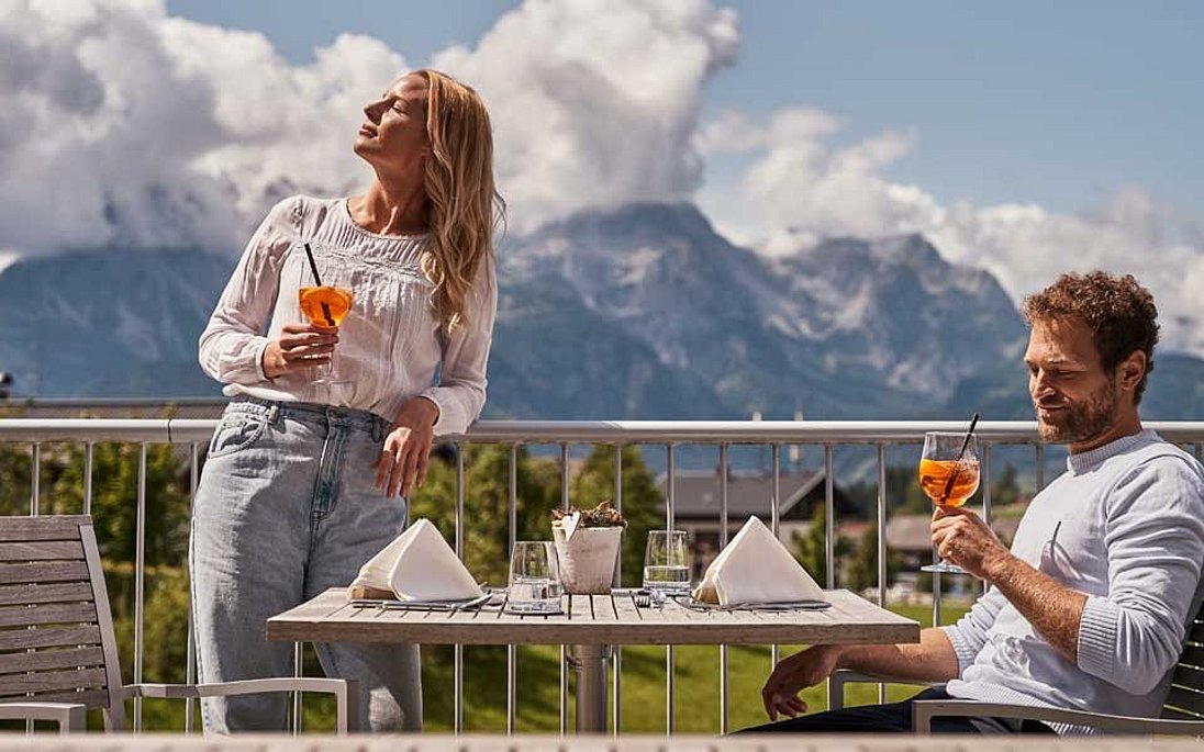 Paar mit Cocktails auf der Terrasse genießt die Sonne