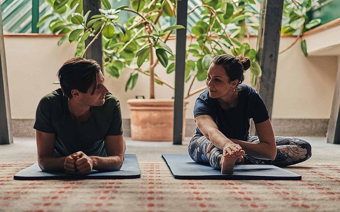 Zwei Gäste unterhalten sich im beim Yogaim  Fitnessraum des Hotels